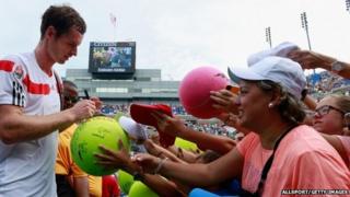 Andy Murray signs a giant tennis ball for a fan