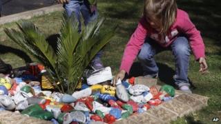 A child place painted pebbles with get-well messages in a garden for former president Nelson Mandela, outside his Johannesburg home Saturday, Aug. 31, 2013.