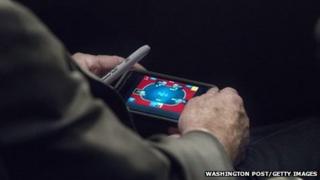 US Senator John McCain plays poker on his iPhone
