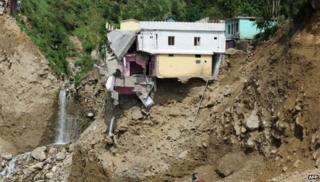 A damaged house perches on the mountainside alongside the Mandakini river at Silli, in the flood affected area of northern Uttarakhand state on July 1, 2013
