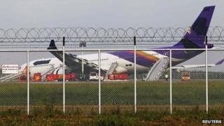 Airport staff work around a Thai Airways plane that skidded off the runaway while landing at Bangkok's Suvarnabhumi Airport on 9 September 2013