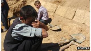 A boy reacts near the grave of his father in a cemetery in Duma neighbourhood of Damascus