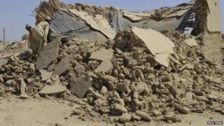 Survivors of an earthquake collect their belongings near the rubble of a mud house after it collapsed following the quake in the town of Awaran, south-western Pakistani province of Baluchistan, September 25, 2013