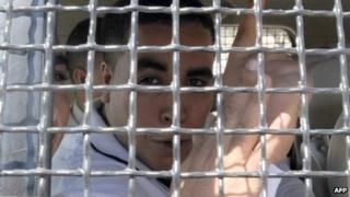 Tunisian rapper Ahmed Ben Ahmed, known as Klay BBJ, gestures behind the bars of a police vehicle as he leaves Hammamet court, Tunisia - 26 September 2013