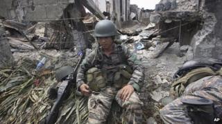 A government trooper rests amidst the ruins at the site of a three-week standoff in Zamboanga city, southern Philippines.