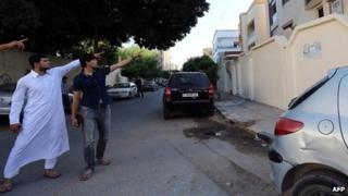 Abdullah al-Raghie (L) and Abdul Moheman al-Raghie (C), the sons of al-Qaeda suspect Abu Anas al-Liby point at the house next to the scene where their father was kidnapped by US special forces (6 October 2013)