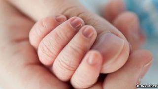 Baby holding adult's thumb. DO NOT REUSE