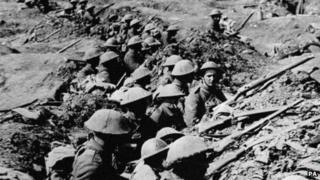 British infantrymen occupying a shallow trench in a ruined landscape