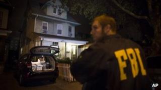 An FBI agent stands guard as evidence sits in the trunk of a vehicle at the Brooklyn residence of Rabbi Mendel Epstein during an investigation, 10 October 2013
