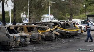 A police officer walks next to burnt vehicles following a fire at Sydney's Olympic Park on 14 October 2013