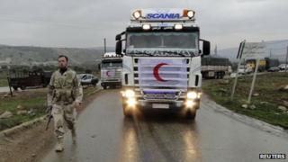 A Free Syrian Army fighter walks in front of a convoy carrying humanitarian aid from the Syrian Arab Red Crescent in Deir Semaan in Aleppo's countryside (file photo)