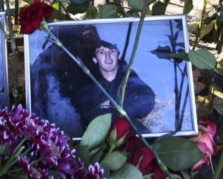 Flowers surround a portrait of Yegor Shcherbakov, 25, who was stabbed to death in a dispute over his girlfriend with another man as the couple returned home in Moscow, 10 October