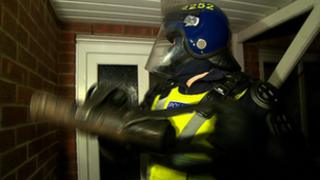 Police officer outside house being raided
