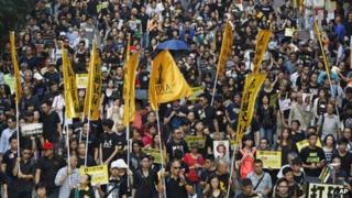 Protesters, many wearing black clothes, march on a Hong Kong street Sunday, Oct. 20, 2013
