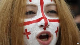 A Georgian woman with face painted in colours of the Georgian flag, attends a rally