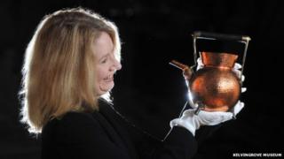Curator Alison Brown with copper kettle designed by Christopher Dresser