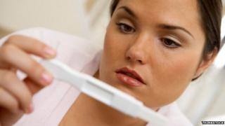 Posed photo of woman looking at pregnancy test