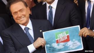 Silvio Berlusconi holding a Forza Italia logo