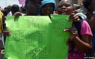 Protesters hold on October 18, 2013 a placard reading "A Real Man Doesn"t Rape !" during a demonstrating in Diepsloot,