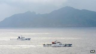 A Japan Coast Guard vessel, left, sails along with a Chinese surveillance ship, right, near disputed islands, rear, called Senkaku in Japan and Diaoyu in China in the East China Sea, 23 April 2013