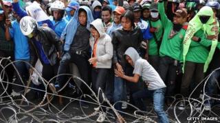 Protesters attempt to dismantle barbed wire barricades during a protest demanding higher wages on 31 October 2013 in Surabaya