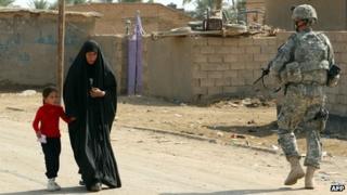 An Iraqi woman walks past a US soldier near a school in the town of Iskandiriyah, Iraq on 27 October 2011