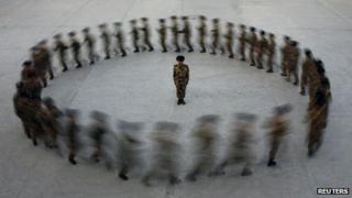 Commander watches paramilitary police recruits run in a circle during training, Xinjiang (file photo - 28 August)