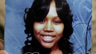 A mourner holds an obituary showing a picture of 19-year-old shooting victim Renisha McBride during her funeral service in Detroit, Michigan 8 November 2013