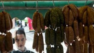 Man looking at sausages in a butcher shop window