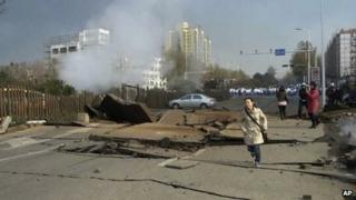 A woman runs near a damaged street following the pipeline explosion in Qingdao