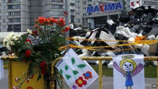 Paintings hang on a fence in front of the Maxima supermarket in Riga, Latvia, Sunday, Nov. 24, 2013