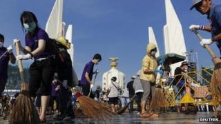 Anti-government protesters sweep the street around the Democracy Monument after weeks of protesting and days of clashes with police in Bangkok's city centre, 4 December 2013