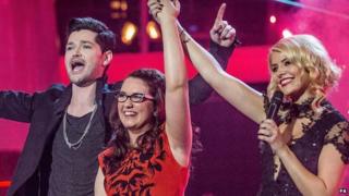 Andrea Begley stands with an arm in the air next to Danny O'Donoghue and Holly Willoughby after winning The Voice.