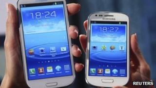 models hold a Samsung Galaxy S and a Galaxy S3 Mini (R) smartphones
