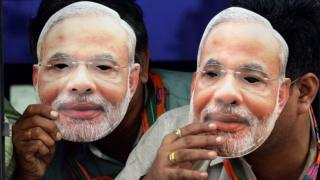 Indian supporters of the Bharatiya Janata Party(BJP) wear masks of Gujarat state Chief Minister and the BJP"s prime ministerial candidate, Narendra Modi, as they travel in a bus towards the airport to receive him in Mumbai on September 30, 2013.