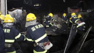 Firefighters clear debris from a market damaged by fire in Shenzhen in south China's Guangdong province, 11 December 2013