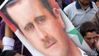 Supporters hold a poster of Syrian President Bashar Assad during a rally on October 12, 2011.
