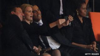David Cameron, Helle Thorning-Schmidt and Barack Obama posing for a selfie, while Michelle Obama sits separately