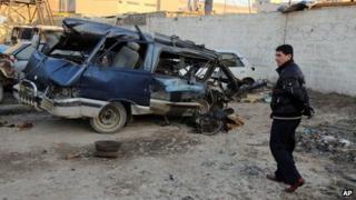 An Iraqi man inspects a minibus damaged in a car bomb attack in Baghdad