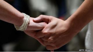 A close-up of two women's hands as they hold hands