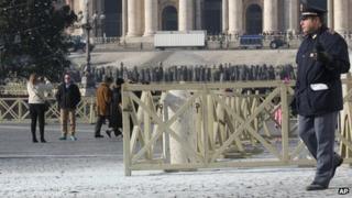 Policeman walks on white powder left from the fire extinguisher in St Peter's Square (19 December 2013)