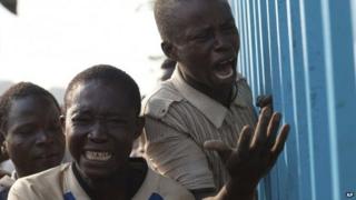 Young men reacts after their friend was badly injured by passing Chadian troops during a protest outside Mpoko Airport in Bangui, Central African Republic, Monday 23 December 2013