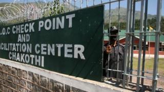 A Kashmiri security guard looks out of the truck check point at the Line of Control (LoC) A
