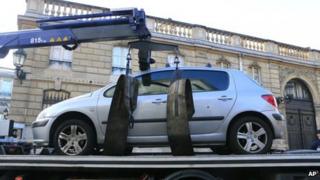 A car is towed away after a driver tried to ram it through a gate of the presidential Elysee Palace on 26 December, 2013.