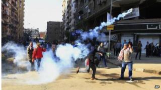 Demonstrator throws tear gas towards security forces in Cairo (27/12/13)
