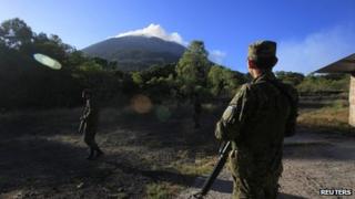 Soldiers stand guard as the Chaparrastique volcano spews ash on 30 December, 2013