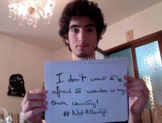 A man holding up a sign which says: "I don't want to be afraid to wander in my own country! #notamartyr"