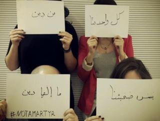 Four people holding up signs in front of their faces which read: "Each of us belongs to a religion but our friendship has no religion #notamartyr"