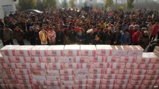 This picture taken on January 14, 2014 shows villagers waiting before a two-metre-long "money wall" built with cash for their year-end bonus at Jianshe village of Lianshan municipality, southwest China"s Sichuan province