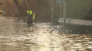 A workman knee deep in flood water
